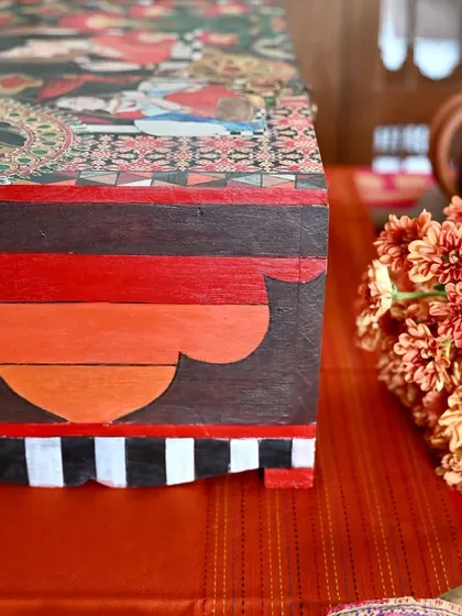 A side view highlighting the hand-painted base and striped border. Every surface of the box is considered, making it a complete work of art from every angle.