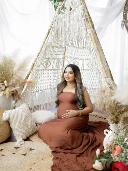 A beautiful portrait in a boho teepee setup. The mom-to-be is seated comfortably, surrounded by pampas grass and macrame details.