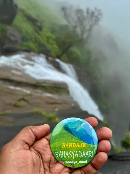 The Bandaje badge held up against the misty falls, a perfect memento of an epic journey.