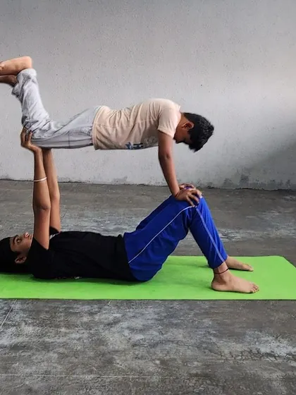 The "flying" partner pose, where the base supports the flyer with their legs, is a foundational acro-yoga skill that builds strength and confidence.