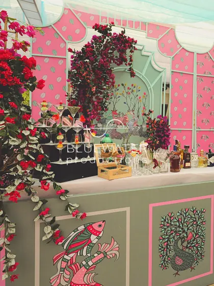 The bar area for the Gond art-themed lunch, featuring a custom-printed facade and a beautiful floral-draped backdrop.