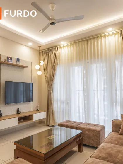 This living room is designed for comfort and entertainment, with a floating TV unit that provides storage while maintaining a light, airy feel. The sheer curtains allow for ample natural light, enhancing the room's welcoming atmosphere.