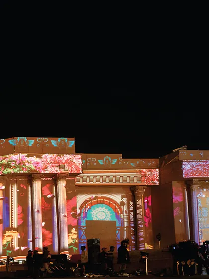 A close-up of the intricate projection mapping on the upper levels of the stage facade. The detail and color transform the stone-like structure into a vibrant work of art.