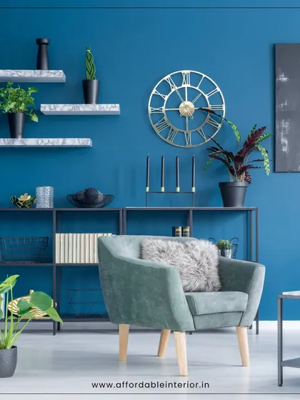 We use bold colors to make a statement. This living room features a deep blue accent wall, floating shelves, and a comfortable armchair, creating a stylish and personalized corner.