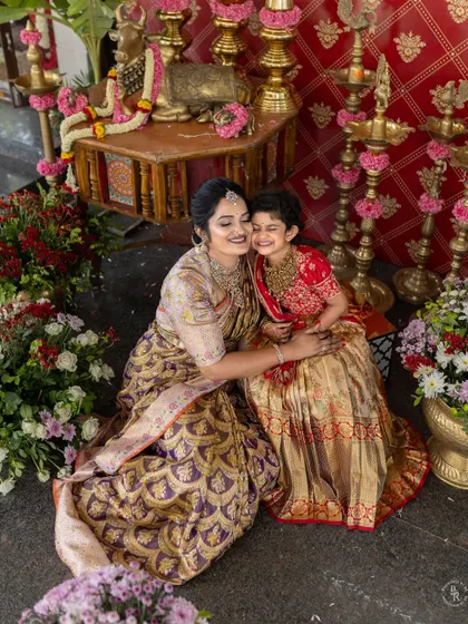 A loving embrace between a mother and her daughter, both dressed in exquisite traditional wear for a family ceremony.