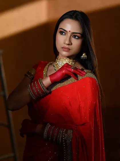 A creative portrait using shadows and pose to convey emotion. The red-stained hands and the simple gold choker are the focal points of this artistic shot.