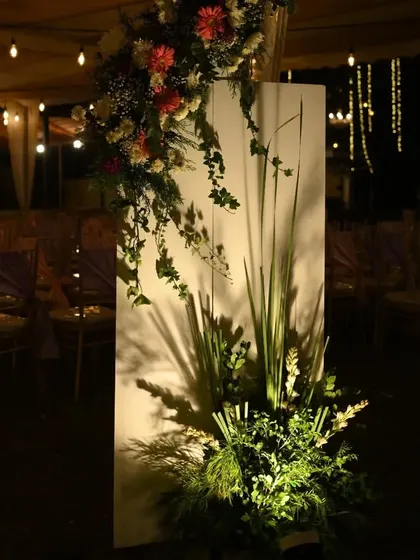 We use uplighting to create drama and highlight decor elements. Here, a floral arrangement on a white panel is beautifully illuminated, casting artistic shadows.