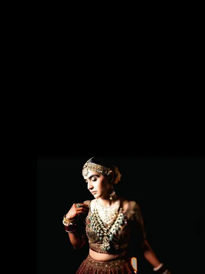 A minimalist and artistic portrait focusing on the bride's face and jewelry against a stark black background.