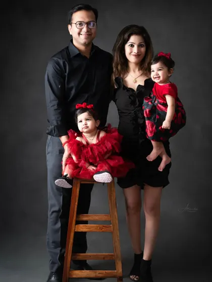 A stylish family portrait, with parents and their twin daughters in a coordinated red and black theme.