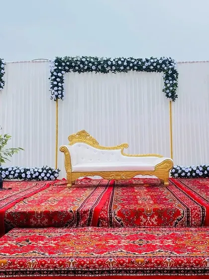 The same Sangeet stage seen during the day, showing the clean lines and the contrast of the white and black flowers.