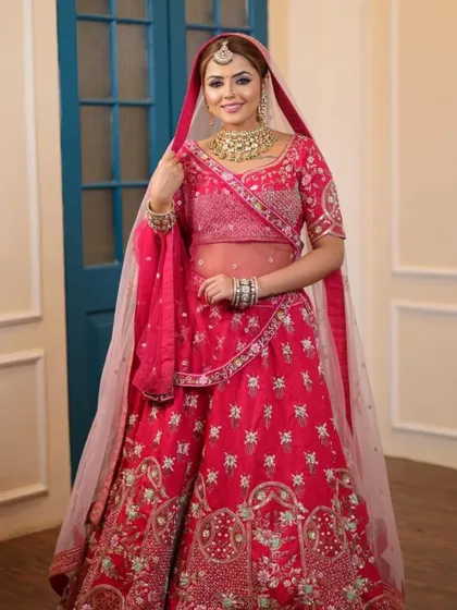 This bride looks elegant and happy in her pink lehenga. The sheer dupatta adds a touch of modern grace to the traditional outfit.