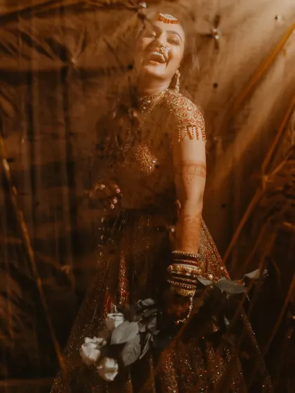 A candid shot of the bride's infectious laughter, captured through a textured foreground for an artistic effect.