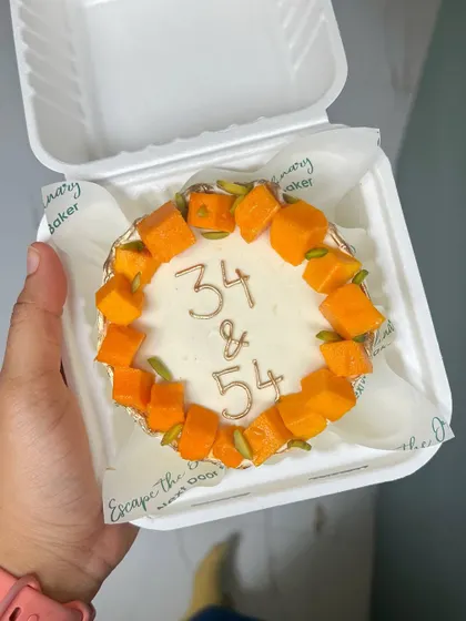 A simple and elegant mango mini cake to celebrate a joint birthday. The cake is topped with fresh Alphonso mango chunks and pistachios, with the ages written in delicate gold.