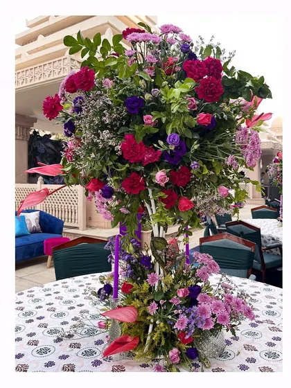 A tall, tree-like centerpiece of purple, pink, and red flowers, designed to bring height and drama to the tables.