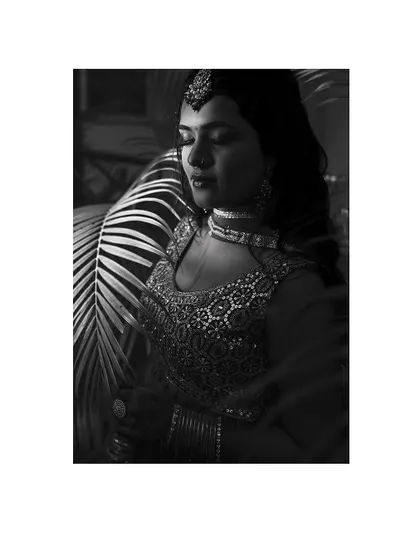 A dramatic black and white portrait of the bride, her face partially obscured by shadow.