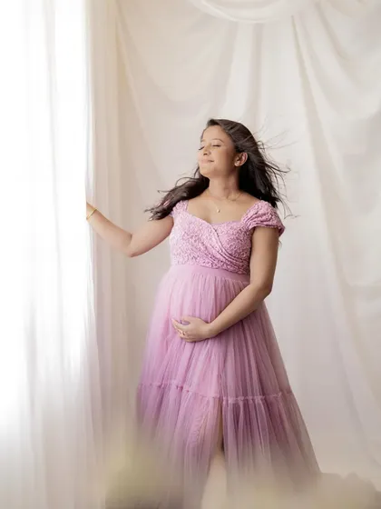 A touch of wind adds beautiful movement to her hair and the delicate fabric of the gown, creating a dynamic and ethereal solo maternity portrait.