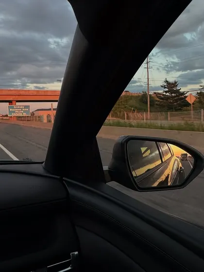 Capturing the sunset reflection in the car mirror while driving on an Ontario highway.