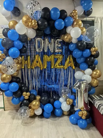 A simple and effective backdrop for a first birthday. I used a blue shimmer curtain, a balloon ring, and foil letters to spell out the baby's name and age.