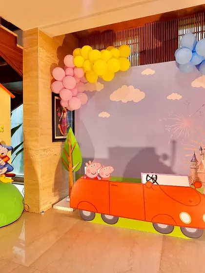 A wide view of the Peppaland and Mickey Mouse crossover party decor. The setup includes Peppa's house, her car, and a sky backdrop with a Disney castle, blending two magical worlds.