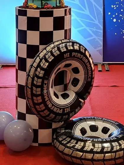 A checkered plinth and inflatable tire props for a racing-themed birthday. These elements help create an authentic racetrack feel for the celebration.