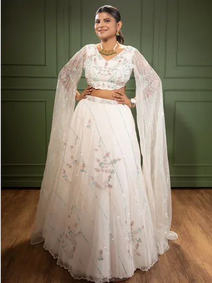 This elegant white lehenga features delicate floral embroidery and dramatic flared sleeves. It’s a timeless piece that is perfect for an engagement party or a sophisticated reception look.