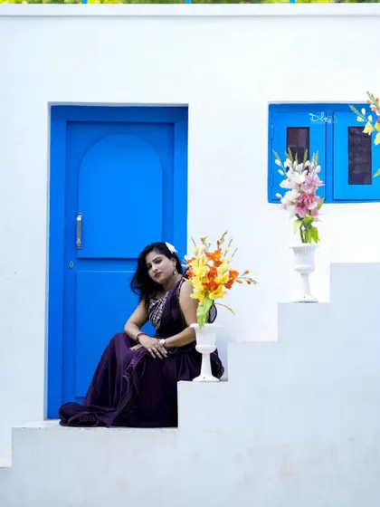 A beautiful photo from a birthday shoot, with the woman seated on the steps of a Santorini-style set.