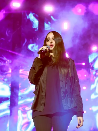 A close-up of Lana Rose singing, with soft purple lighting. This intimate shot focuses purely on the artist's expression and passion.