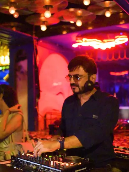 In action at the console, surrounded by the neon lights of the club. This is where the magic happens.