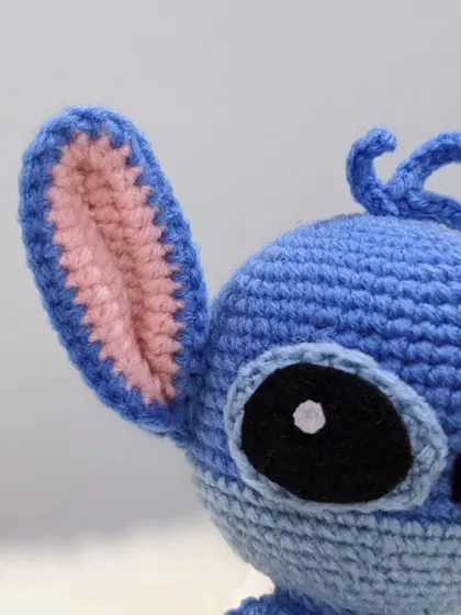 A detailed close-up of the Stitch amigurumi, showing the careful stitching on his ear and eye.