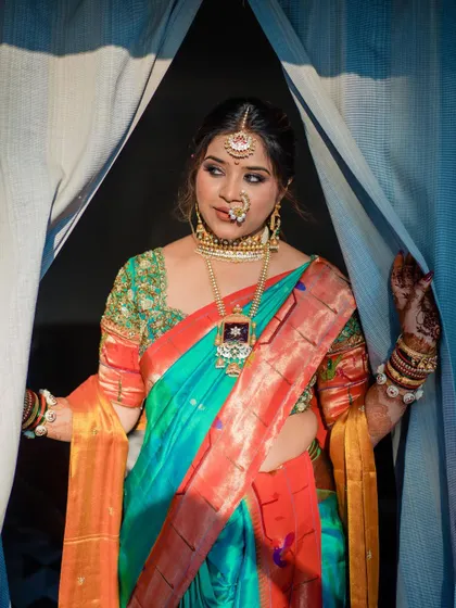A dramatic bridal portrait, with the bride framed by curtains, showcasing her stunning traditional look.