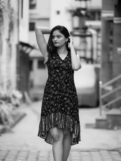 A classic full-body portrait in an urban alley. The black and white tones emphasize the textures of the location and her thoughtful pose.