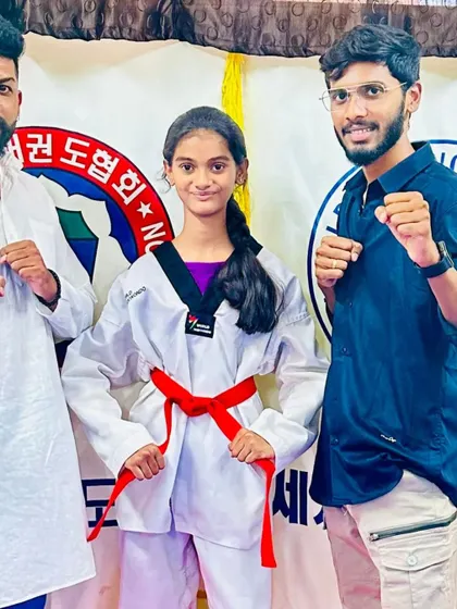 A young lady celebrates her new red belt with her coaches.