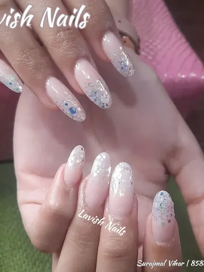 A subtle glitter fade with fine, iridescent glitter over a milky white base, creating a delicate and ethereal look on long almond nails.