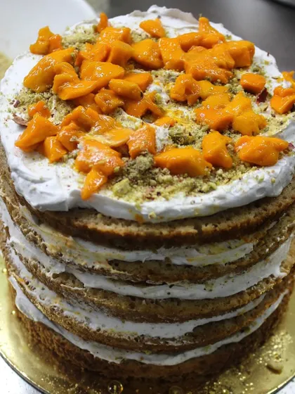 A behind-the-scenes look at the layering of our Mango Pistachio masterpiece, showing generous amounts of fresh mango and crushed pistachios between cake layers.