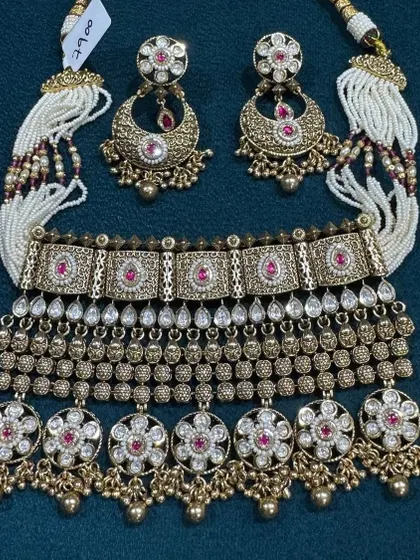 An absolutely stunning antique bridal choker set. It features multiple layers of fine work, including Polki, pearls, and floral motifs with ruby stones. This is a complete, heavy set for the bride who wants a traditional Rajwada look.