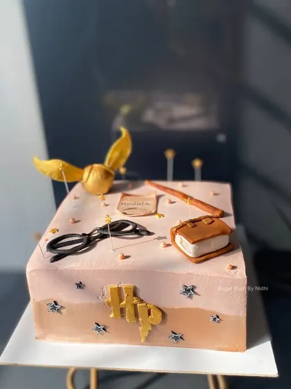 A magical Harry Potter themed cake, designed to look like a spell book. This 2kg Chocolate Hazelnut Praline cake features a golden snitch, a wand, and other iconic elements from the series.
