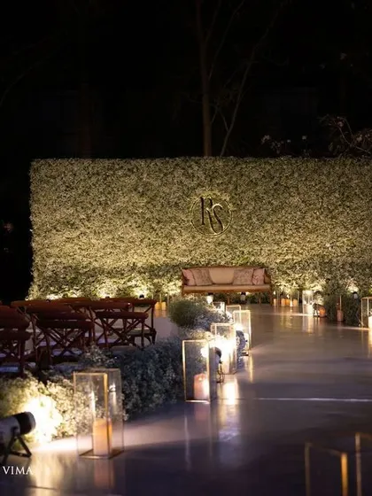 An ethereal all-white reception. The aisle and backdrop are adorned with clouds of baby's breath, while flickering candles cast a warm, romantic glow, creating a scene straight out of a fairy tale.
