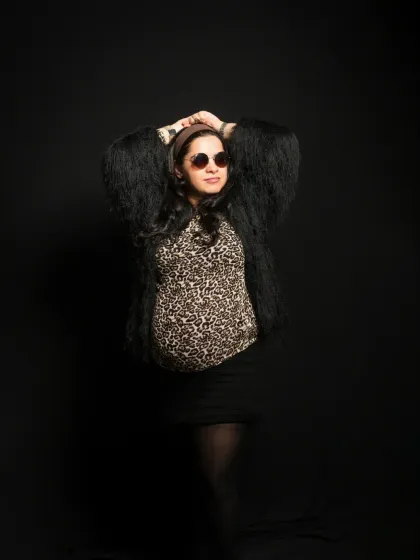 A fun and glamorous maternity portrait with a touch of wild style. The leopard print top and faux fur jacket show that maternity fashion can be bold and expressive.