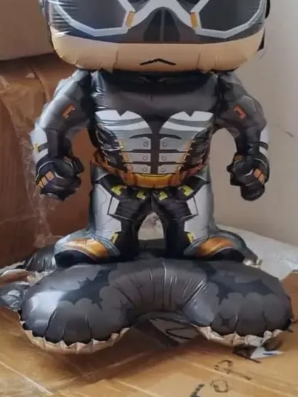 A fun, stylized Batman foil balloon that can be filled with air to stand on its own. It's a perfect addition to a superhero-themed birthday party table or gift area.