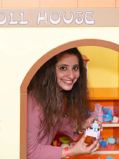 A mother joins in on the fun, playing with her child inside the dollhouse.