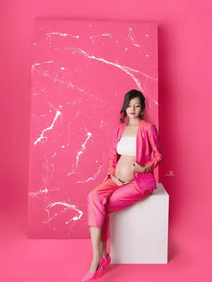 A confident and cool seated pose in a bright pink suit. This look is perfect for the mom-to-be who wants to celebrate her pregnancy with a modern and stylish flair.