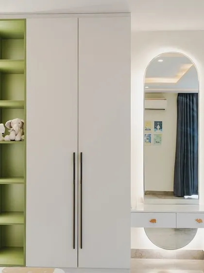 A close-up of the wardrobe and dressing table in the kids' room. The arched mirror with backlighting is a beautiful feature, and the open shelving with a green accent adds a pop of color.