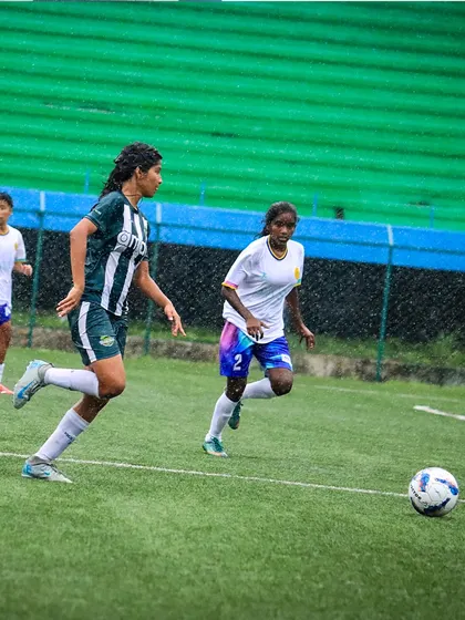 The game goes on, even in the rain. A player chases down a loose ball, showing resilience and love for the game.
