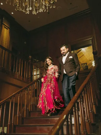 The couple makes their way down the grand staircase, hand in hand. Their classic, elegant outfits are perfect for a formal pre-wedding dinner.