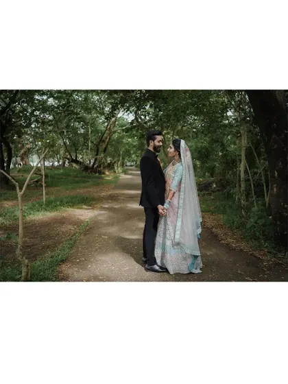 A wide shot of the couple standing on a path in a beautiful park, a classic and timeless pre-wedding portrait.