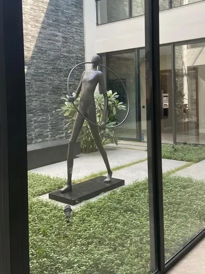 An angled shot of the courtyard sculpture, highlighting the play of light and shadow on its form and the surrounding stone wall. This demonstrates how we consider natural light in our designs to create evolving visual experiences.
