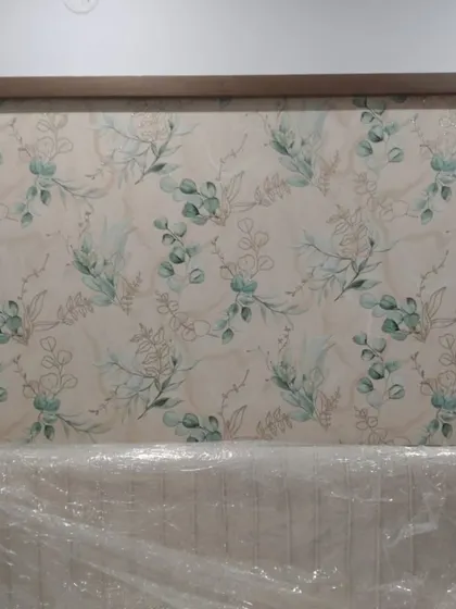 A delicate eucalyptus branch wallpaper framed above a headboard. This is a beautiful example of using wallpaper as a subtle and elegant piece of decor.