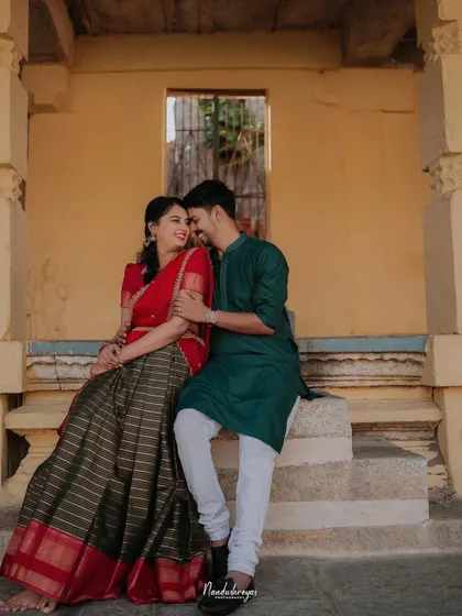 A couple sits on the steps of a temple structure, sharing a quiet moment of connection. The warm tones of the stone and their traditional attire create a beautiful, cultural pre-wedding portrait.