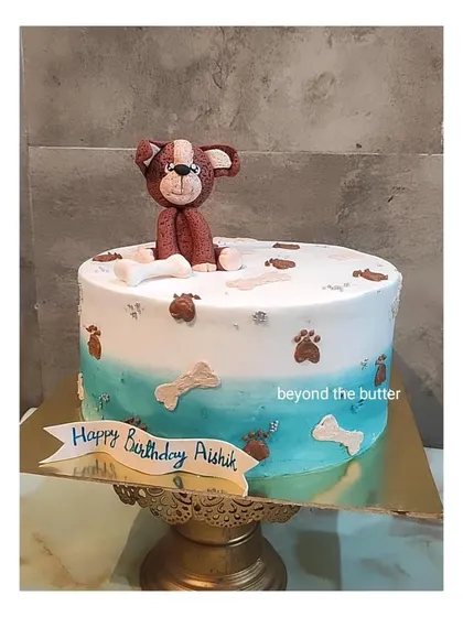 A cute puppy themed cake for a birthday boy. This design features a hand modeled fondant dog, paw prints, and dog bones.