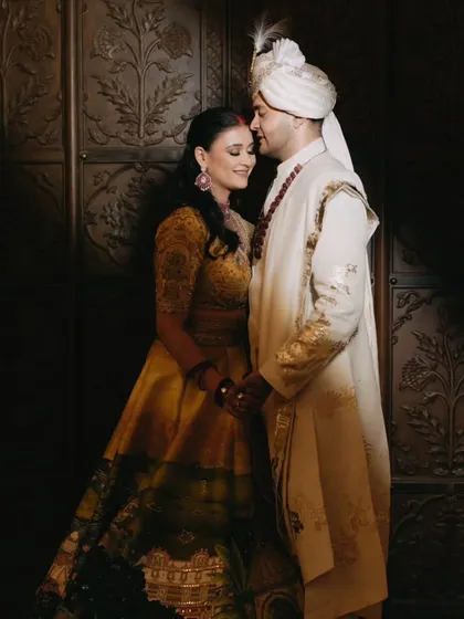 A classic, romantic portrait of the couple against a beautifully carved wooden door, exuding elegance and grace.